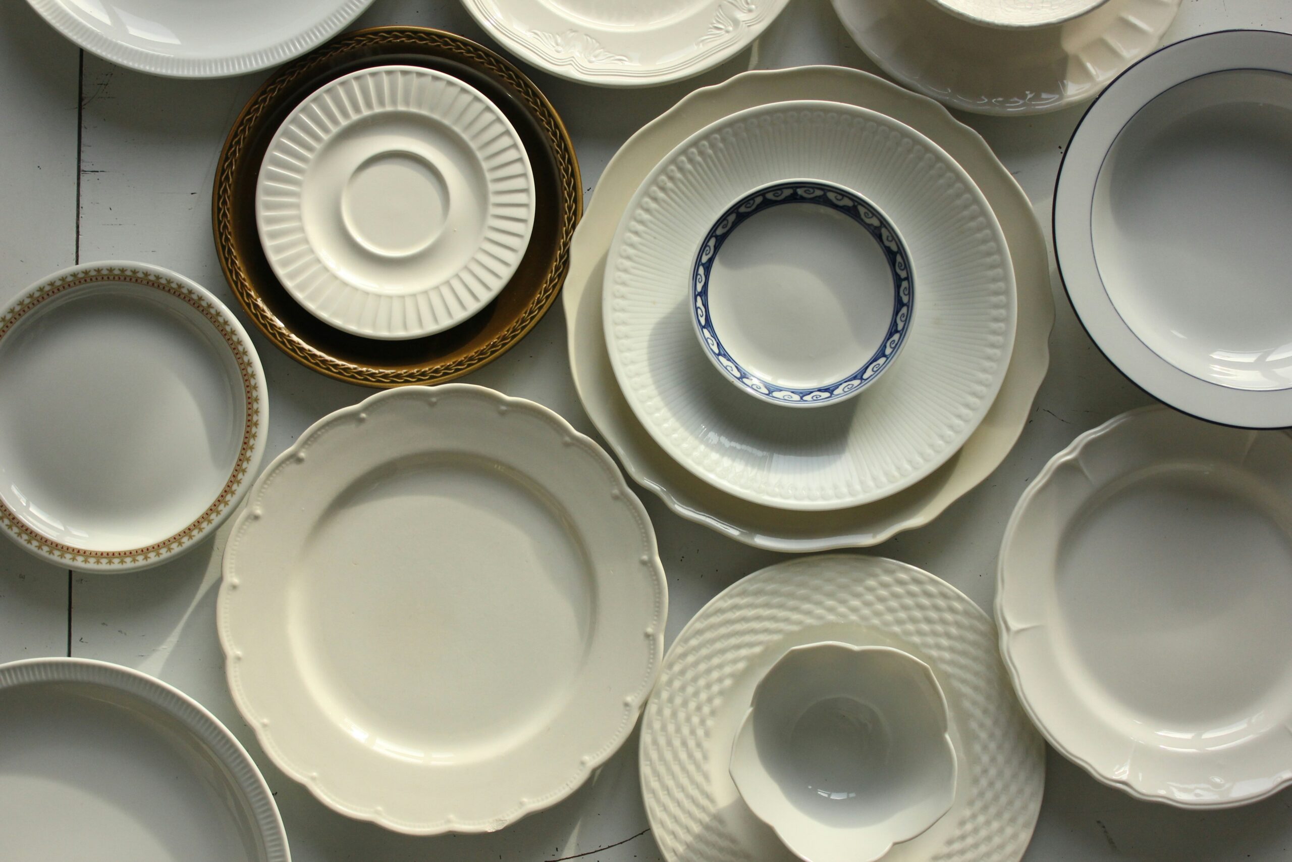 Assorted white ceramic plates, bowls, and serving dishes arranged in a flat lay display